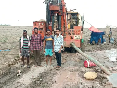Drilling crew standing in front of an orange rig in a muddy field